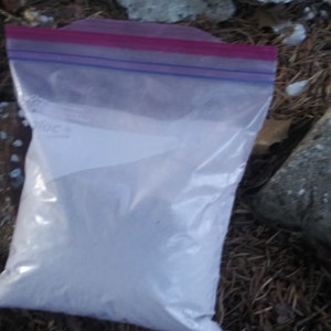May include: A white powder in a clear plastic bag with a red and blue zipper closure.