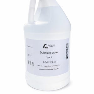 May include: A clear plastic container of deionised water, with a white cap and handle. The label states "Deionized Water Type II" and "1 Gal/ 128 oz". The attributes are listed as Vegan, Organic, and Paraben-Free.