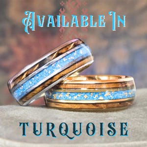 May include: Two rings featuring wood grain bands with a central inlay of crushed turquoise and metallic flakes. The top ring has silver-toned metal edges, while the bottom ring has gold-toned metal edges. Text reads: AVAILABLE IN TURQUOISE.