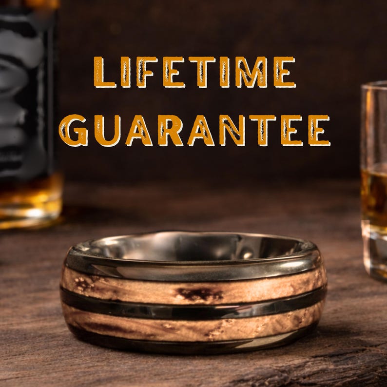 May include: A ring featuring a polished dark metal band with two inlaid textured wood segments. The text LIFETIME GUARANTEE is displayed in orange letters above the ring, which is positioned between two glass containers.