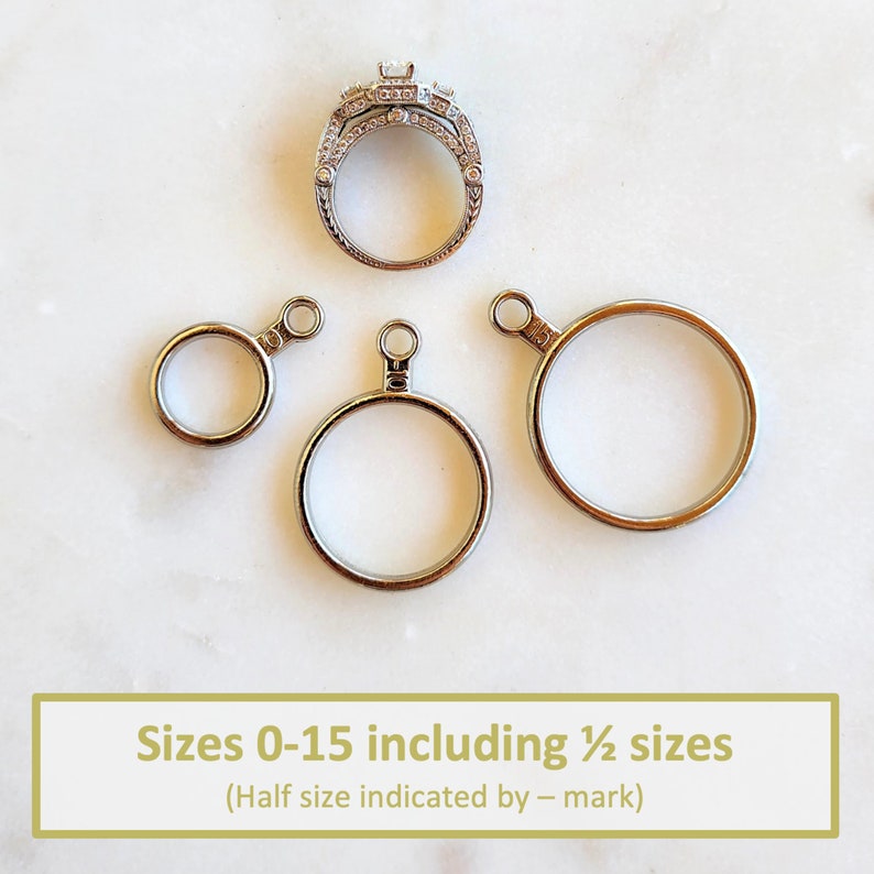 May include: A silver-toned ring sizer set featuring three circular metal rings of varying diameters, each with a small loop at the top. The rings are marked with the numbers 0, 10, and 15. Text at the bottom reads: Sizes 0-15 including &frac12; sizes (Half size indicated by &ndash; mark).