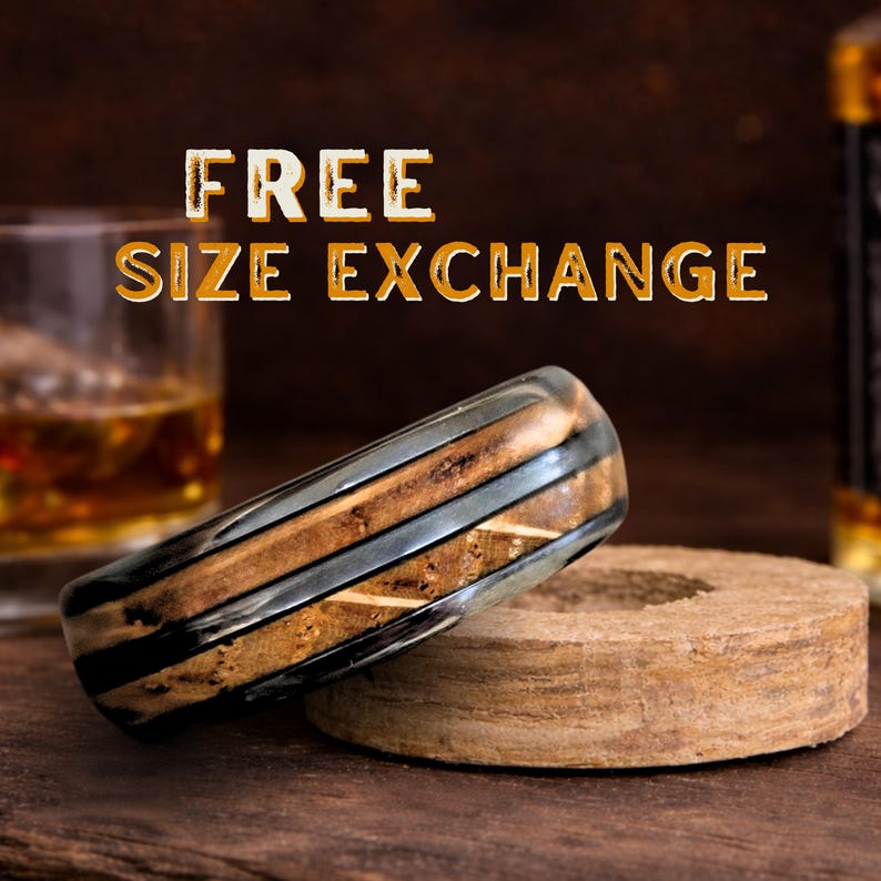 May include: A ring featuring a layered design with alternating bands of dark, smooth material and textured, light brown wood grain. The text FREE SIZE EXCHANGE is displayed in bold, light-colored letters above the ring in the background.