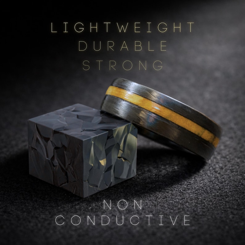 May include: A dark gray ring with a central light brown inlay positioned next to a dark gray cube with a faceted, geometric surface. The text LIGHTWEIGHT, DURABLE, STRONG, and NON CONDUCTIVE is displayed in thin, light-colored capital letters.
