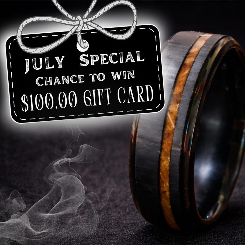 Puede incluir: Un anillo negro con una incrustaci&oacute;n central de material marr&oacute;n texturizado. Una etiqueta rectangular negra con texto blanco que dice JULY SPECIAL CHANCE TO WIN $100.00 GIFT CARD, con un dibujo lineal blanco de un lazo.