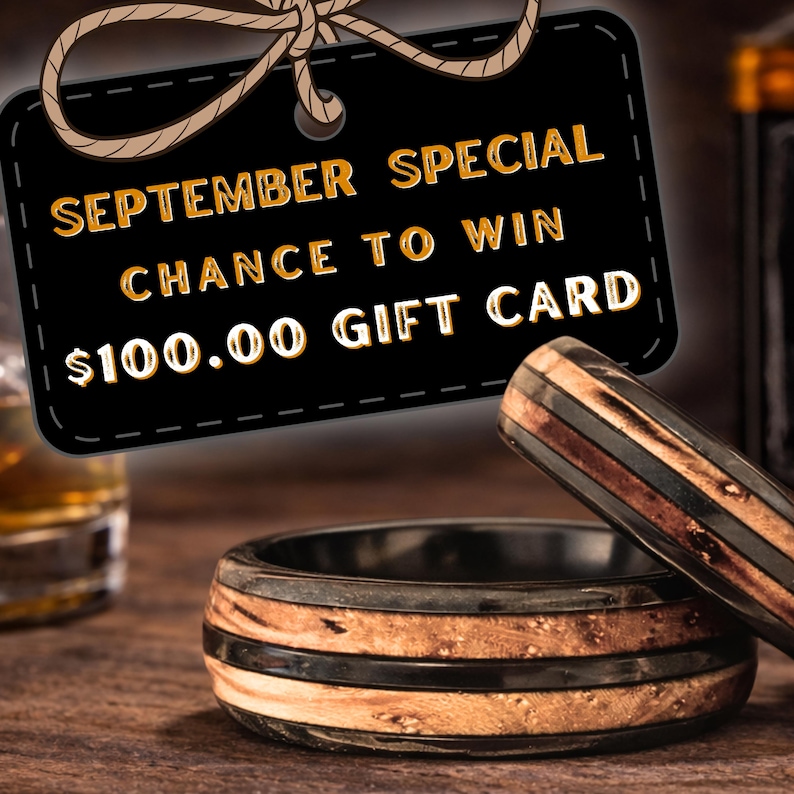 May include: Two rings featuring a layered design with a dark black band and a natural light brown wood inlay. A black rectangular tag with a rope tie displays the text SEPTEMBER SPECIAL CHANCE TO WIN $100.00 GIFT CARD in gold lettering.