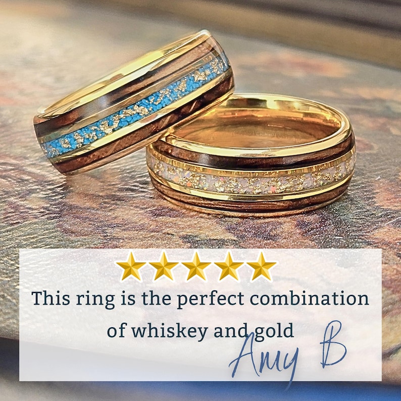 May include: Two rings featuring gold bands with dark wood inlays. One ring has a central inlay of turquoise and gold flakes, while the other features a white and gold flake inlay. Text reads: This ring is the perfect combination of whiskey and gold.