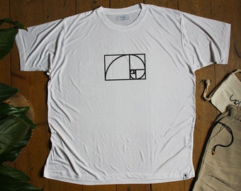 Peut inclure: T-shirt blanc avec un motif géométrique noir sur le devant. Le t-shirt a un col rond et des manches courtes. Le t-shirt est posé sur une surface en bois. Le mot "Solify" est imprimé sur l'étiquette.