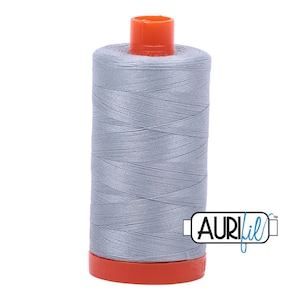 May include: A spool of silver gray thread with an orange plastic bobbin and the text "Aurifil" on the label.
