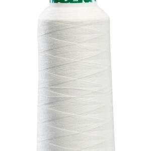 May include: A spool of white sewing thread with the brand name "MADEIRA" in green letters. The thread is tightly wound, creating a textured surface. The spool's top is white, and the thread is a bright, clean white.