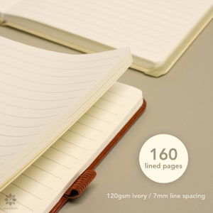May include: A brown leather bound journal with 160 lined pages. The pages are ivory colored with 7mm line spacing. The journal is open to show the lined pages.