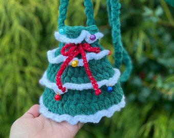 May include: A handmade green crochet bag shaped like a Christmas tree, with white trim and a red bow. The bag has a green strap and is decorated with colorful beads. The text "Christmas tree Bag Pattern" is at the bottom.