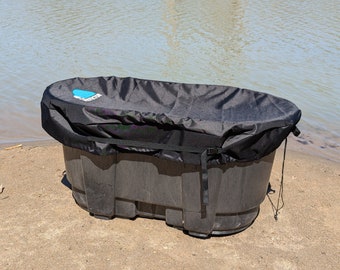 May include: A black plastic tub with a black cover. The tub is sitting on a sandy beach.