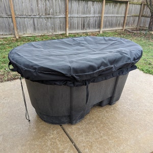 May include: Black oval-shaped hot tub cover with a drawstring closure. The cover is made of a thick, durable material and is designed to protect the hot tub from the elements.