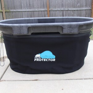 May include: A large, round, gray plastic tub with a black fabric cover. The cover features a blue and white logo that reads "POLAR PROTECTOR". The tub sits on a concrete surface, with a wooden fence in the background.