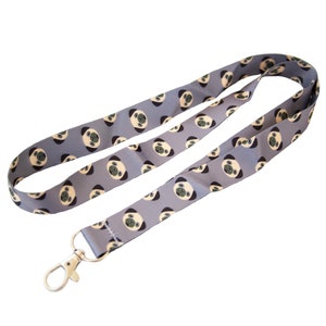 May include: A gray lanyard with a repeating pattern of pug faces. The lanyard has a silver swivel clip.