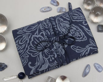 May include: A blue fabric pouch with a white floral pattern, tied with a blue ribbon. The pouch is surrounded by various crystals and stones.