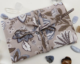 May include: A beige fabric pouch with a floral pattern in shades of blue, brown, and white. The pouch is tied with a brown ribbon and is surrounded by various crystals and stones.