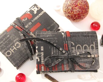 May include: Two small black and red fabric journals with black ribbon ties. The journals have a vintage newspaper print design with the words "Good Morning" and "Good" printed on the covers.