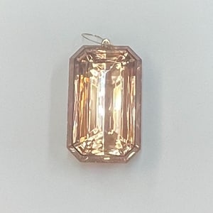 May include: A large, faceted, light brown gemstone pendant with a silver loop at the top.