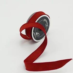 May include: A spool of red velvet ribbon with a black label that says "The Ribbon Lady".