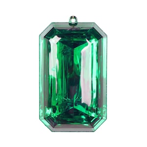 May include: A large, emerald green, faceted, plastic gem ornament. The ornament is shaped like a rectangular emerald with a gold loop at the top for hanging.