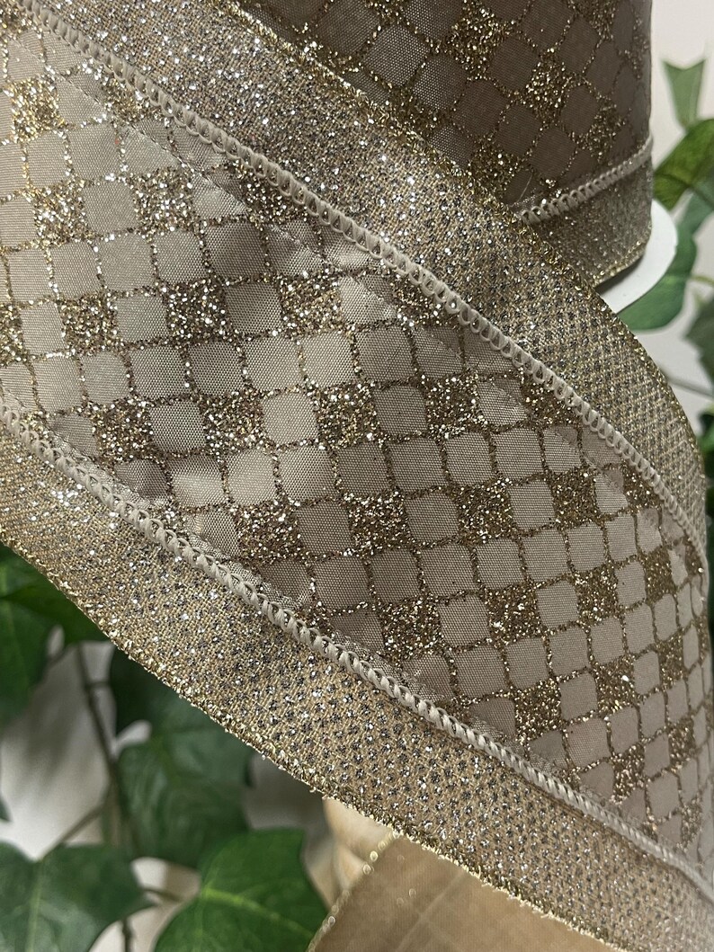Peut inclure: Gros plan sur un ruban d&eacute;coratif avec un motif scintillant dor&eacute;. Le ruban pr&eacute;sente un motif quadrill&eacute; avec une bordure scintillante. Le ruban est de couleur beige neutre, adapt&eacute; &agrave; divers projets d'artisanat et d'emballage cadeau.