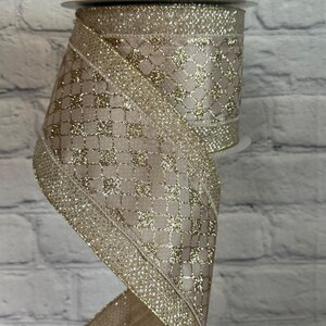 Peut inclure: Rouleau de ruban d&eacute;coratif avec un fond beige et un motif dor&eacute; en forme de grille. Les bords sont orn&eacute;s de paillettes dor&eacute;es. Le ruban est partiellement d&eacute;roul&eacute;, r&eacute;v&eacute;lant sa texture et son design. Id&eacute;al pour l'artisanat ou l'emballage de cadeaux.