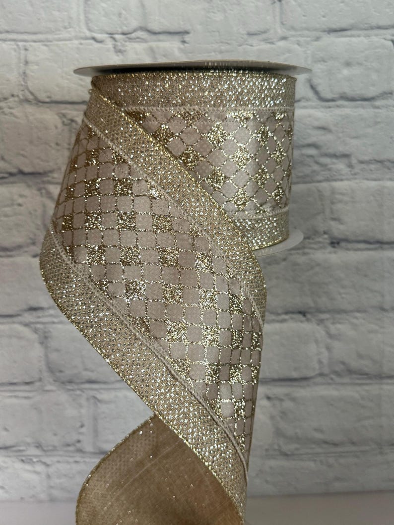 Peut inclure: Rouleau de ruban d&eacute;coratif avec un fond beige et un motif dor&eacute; en forme de grille. Les bords sont orn&eacute;s de paillettes dor&eacute;es. Le ruban est partiellement d&eacute;roul&eacute;, r&eacute;v&eacute;lant sa texture et son design. Id&eacute;al pour l'artisanat ou l'emballage de cadeaux.