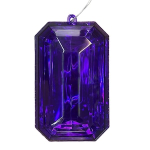 May include: A large, purple, plastic, faceted gem ornament with a silver string for hanging.