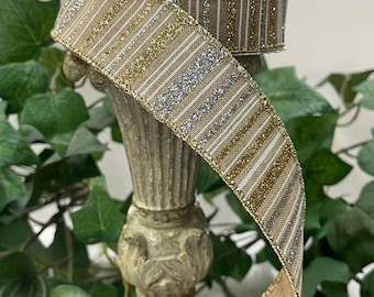 May include: A beige ribbon with gold and silver glitter stripes. The ribbon is wrapped around a decorative stand.