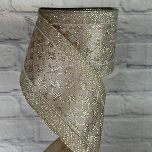 Peut inclure: Rouleau de ruban d&eacute;coratif avec un fond beige et un rev&ecirc;tement dor&eacute; et scintillant. Le ruban pr&eacute;sente un motif de losanges et est bord&eacute; d'une bordure dor&eacute;e scintillante. Id&eacute;al pour l'artisanat, l'emballage de cadeaux et les d&eacute;corations de f&ecirc;tes.