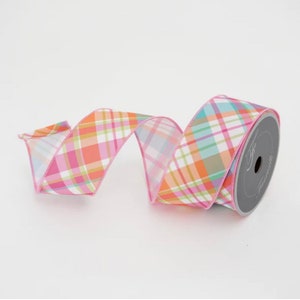 May include: A roll of decorative ribbon with a plaid pattern in shades of pink, orange, green, and blue. The ribbon is on a white background. The ribbon is ideal for crafts, gift wrapping, and decorations.