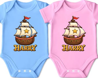Könnte beinhalten: Zwei kurzärmelige Babybodys, einer in Hellblau und einer in Hellrosa, jeweils mit einer Cartoon-Illustration eines braunen Holzsegelschiffs mit weißen Segeln, einem gelben Stern und einer Schatztruhe sowie dem Namen HARRY darunter.