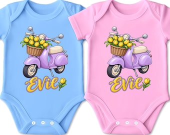 Könnte beinhalten: Ein hellblauer und ein hellrosa Babybody, jeweils mit einer Grafik eines lila Rollers mit einem Weidenkorb voller gelber Tulpen. Unter dem Roller ist das Wort "EVIL" in einer gelben Schreibschrift neben einer einzelnen Tulpe abgebildet.
