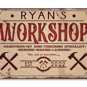May include: A vintage-style metal sign with a rustic background and red text that reads "Ryan's Workshop." The sign also includes the text "Handyman DIY King-Tinkering Specialist." and "Mending Making Laughing."  The sign also includes the text "No Job is Too Small." and "Est. 2022".