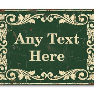 May include: A rectangular, distressed green metal sign with the words "Any Text Here" in white. The sign features an ornate, cream-coloured floral border and a rusty brown edge.