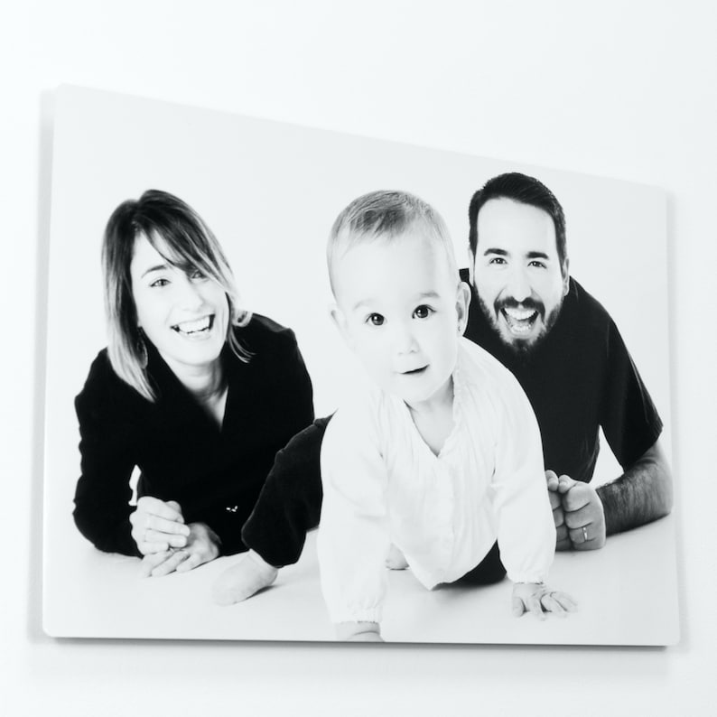 Pu&ograve; includere: Foto in bianco e nero di una famiglia. Una donna con i capelli scuri &egrave; sdraiata a pancia in gi&ugrave;, guardando la fotocamera. Un uomo con i capelli scuri &egrave; sdraiato di lato, guardando la fotocamera. Un bambino sta gattonando verso la fotocamera, guardando la fotocamera.