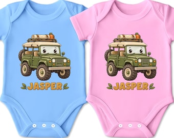 Könnte beinhalten: Zwei kurzärmelige Bodys, einer in Hellblau und einer in Hellrosa, jeweils mit einem Cartoon-Geländewagen in Olivgrün mit Dachgepäckträger und dem Namen JASPER in orangefarbenen Buchstaben unter dem Fahrzeug, flankiert von zwei kleinen grünen Blättern.