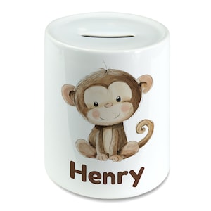 Könnte beinhalten: Weiße Keramik-Sparbüchse mit einer Cartoon-Affenillustration und dem Namen "Henry" in braunen Buchstaben.