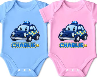 Könnte beinhalten: Zwei kurzärmelige Babybodys, einer in Hellblau und einer in Hellrosa, jeweils mit einem dunkelblauen Cartoon-Polizeiauto mit gelb-blauem Karomuster an der Seite, einem blauen Blaulicht auf dem Dach und dem Namen CHARLIE in gelber Schrift.