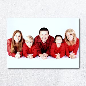Pu&ograve; includere: Una famiglia di cinque persone, due adulti e tre bambini, sono sdraiati a pancia in gi&ugrave; e sorridono alla telecamera. Indossano tutti camicie rosse. Lo sfondo &egrave; bianco.
