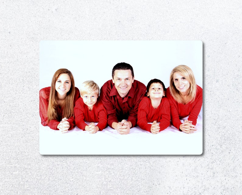 Pu&ograve; includere: Una famiglia di cinque persone, due adulti e tre bambini, sono sdraiati a pancia in gi&ugrave; e sorridono alla telecamera. Indossano tutti camicie rosse. Lo sfondo &egrave; bianco.
