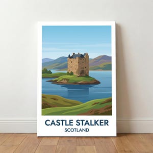 Op de afbeelding: Een canvas print met een illustratie van Castle Stalker in Schotland. Het kasteel, gemaakt van bruine steen, staat op een eiland in een blauw meer. De print bevat de tekst "CASTLE STALKER SCOTLAND" in marineblauw.