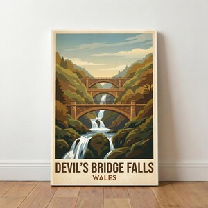 May include: A framed print depicting Devil's Bridge Falls in Wales. The image shows three stone arch bridges spanning a waterfall, surrounded by green and brown trees. The sky is a pale blue with clouds. The text "DEVIL'S BRIDGE FALLS WALES" is at the bottom.
