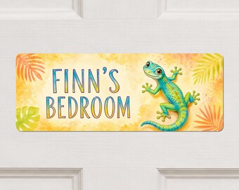 May include: A rectangular sign with a yellow watercolour background featuring the text FINN'S BEDROOM in blue and yellow gradient letters. A blue and green gecko with orange spots is positioned on the right side, surrounded by palm leaf illustrations.