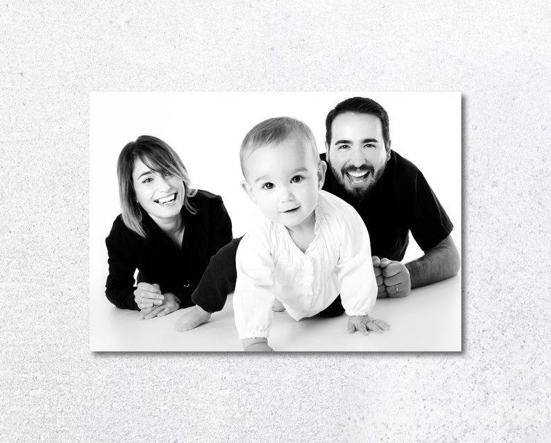 Pu&ograve; includere: Una fotografia in bianco e nero di una famiglia con una madre, un padre e un bambino. La madre sorride e guarda la fotocamera. Il padre sorride e guarda la fotocamera. Il bambino sta gattonando verso la fotocamera.
