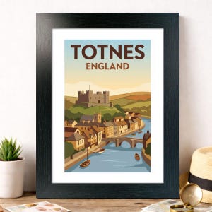 Puede incluir: Impresión enmarcada de Totnes, Inglaterra, con un diseño de cartel de viaje vintage. La obra de arte muestra un castillo en una colina, un río y edificios. El texto "TOTNES ENGLAND" se muestra en la parte superior en marrón. El marco es negro.