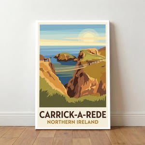 May include: A framed print of Carrick-a-Rede, Northern Ireland. The artwork shows a coastal scene with a rope bridge between cliffs. The sky is blue with a sun, and the water is a deep blue. The print has the text "Carrick-a-Rede Northern Ireland."