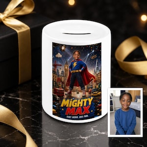 Può includere: Un salvadanaio in ceramica bianca con una stampa grafica di un bambino vestito da supereroe con mantello rosso e maglia blu, in uno scenario cittadino con il testo MIGHTY MAX TINY HERO, BIG FUN stampato sotto la figura.
