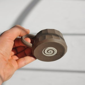 May include: A brown ceramic mug with a white spiral design and the text "Born Wild" on the bottom.